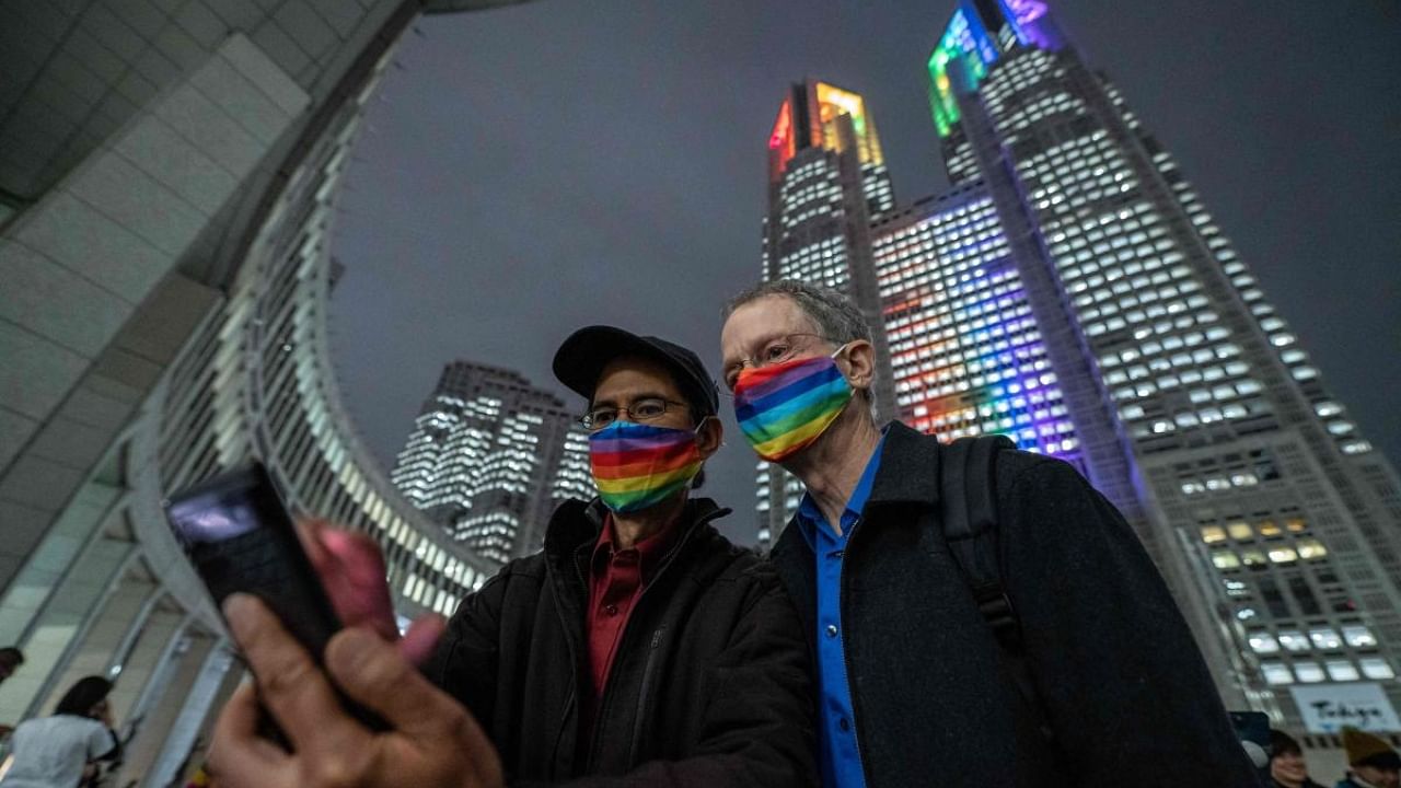 People take selfie in front of the Tokyo Metropolitan Government building illuminated with rainbow lights in Shinjuku district of Tokyo on November 1, 2022. - Tokyo began issuing partnership certificates to same-sex couples who live and work in the capital on November 1. Credit: AFP Photo
