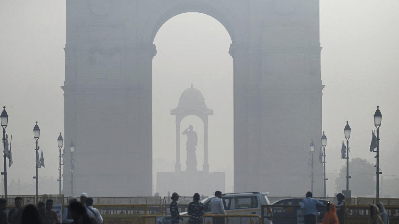 Pedestrians walk along a road near the India Gate amid heavy smog in New Delhi. Credit: AFP Photo