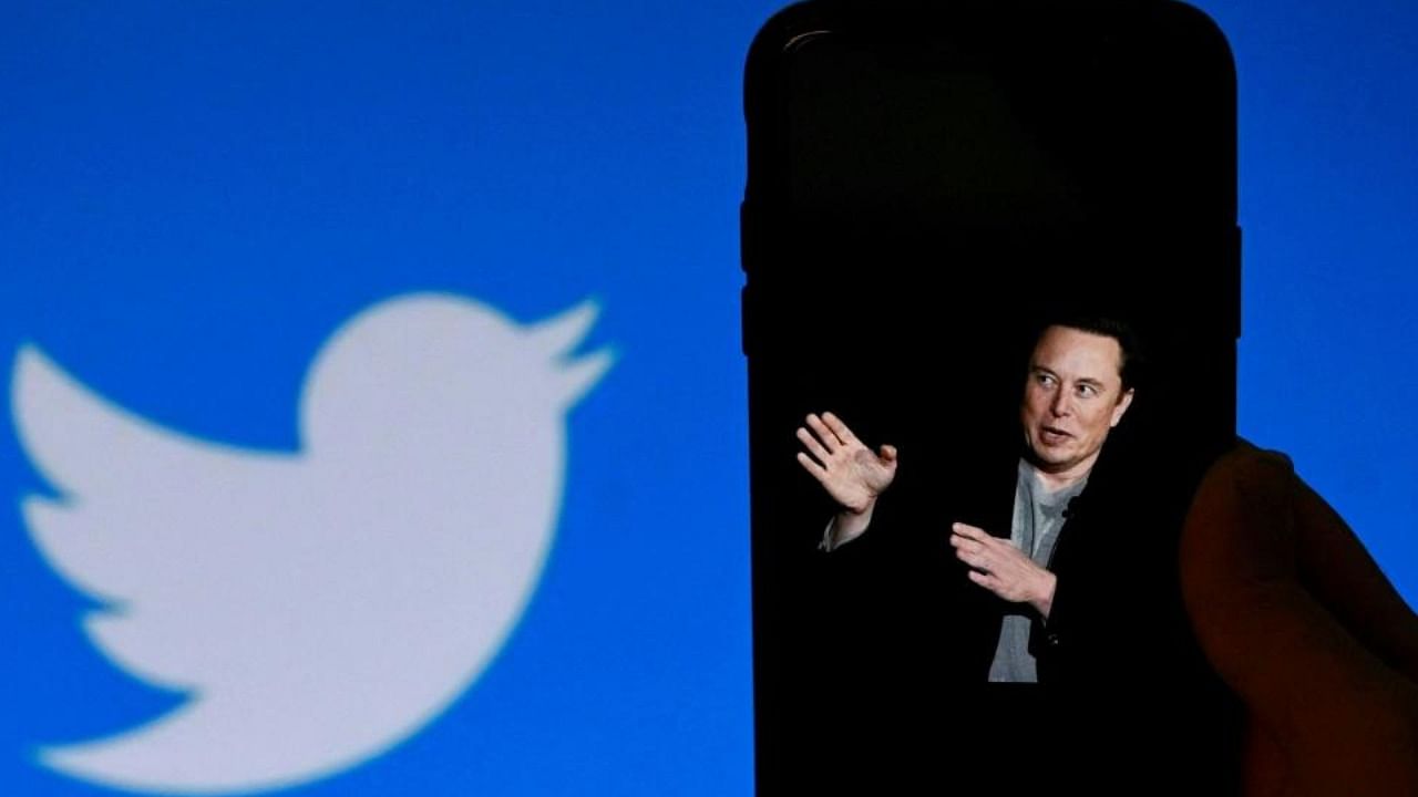 A phone screen displays a photo of Elon Musk with the Twitter logo shown in the background. Credit: AFP Photo