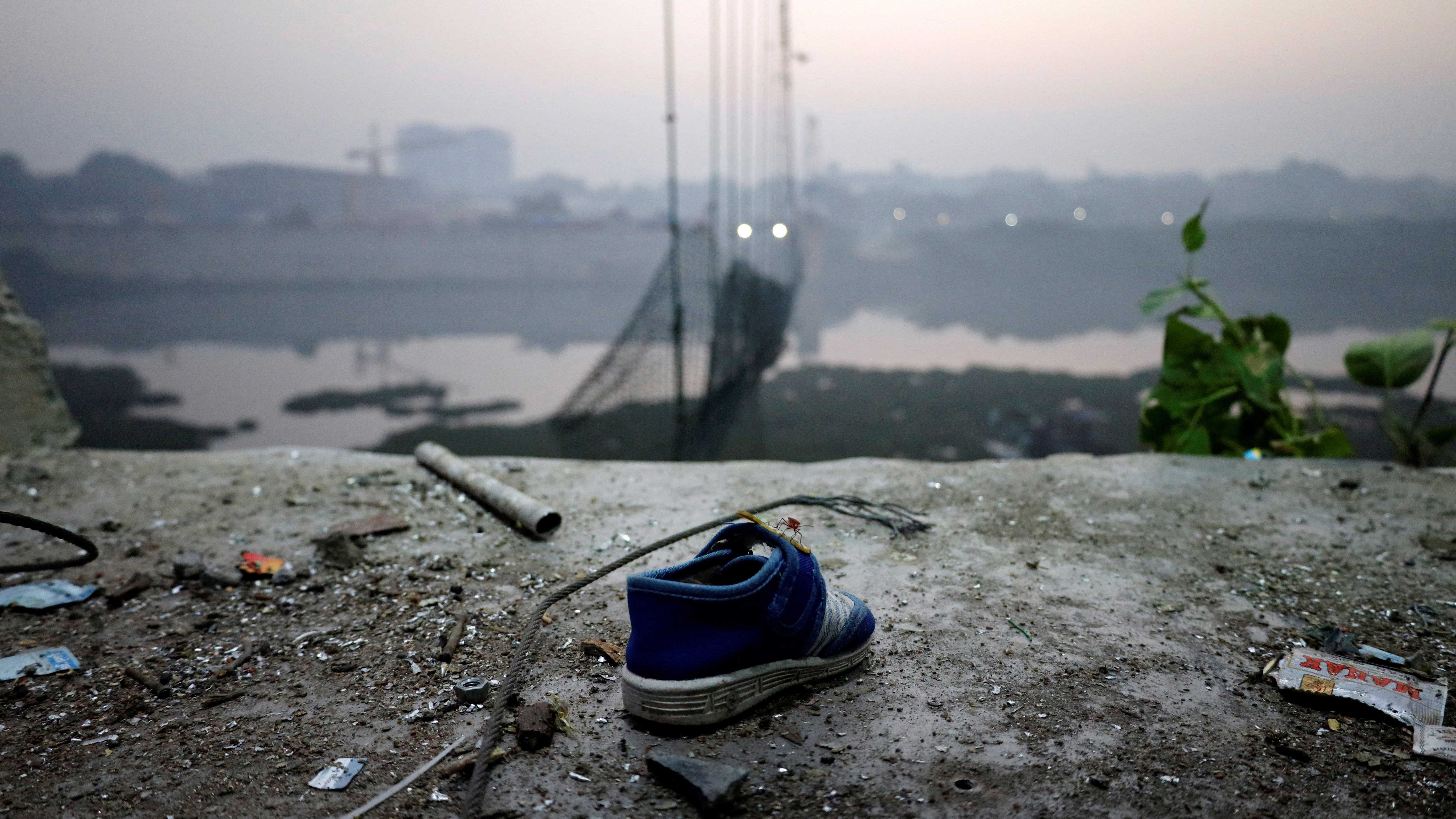 A shoe lies near a damaged suspension bridge after it collapsed in Morbi town, Gujarat. Credit: Reuters Photo