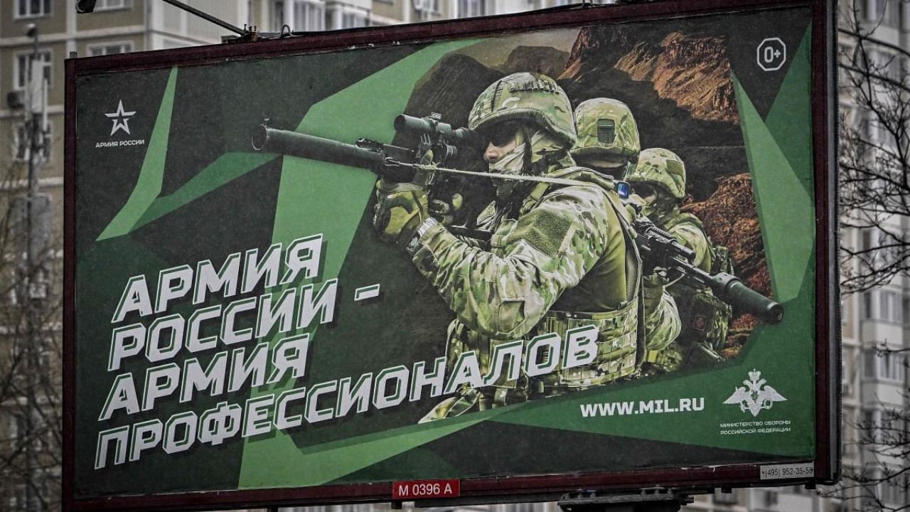 A photograph taken on October 24, 2022 shows a poster displaying Russian soldiers with a slogan reading 'Army of Russia - Army of professionals' decorating a street in Moscow. Credit: AFP Photo