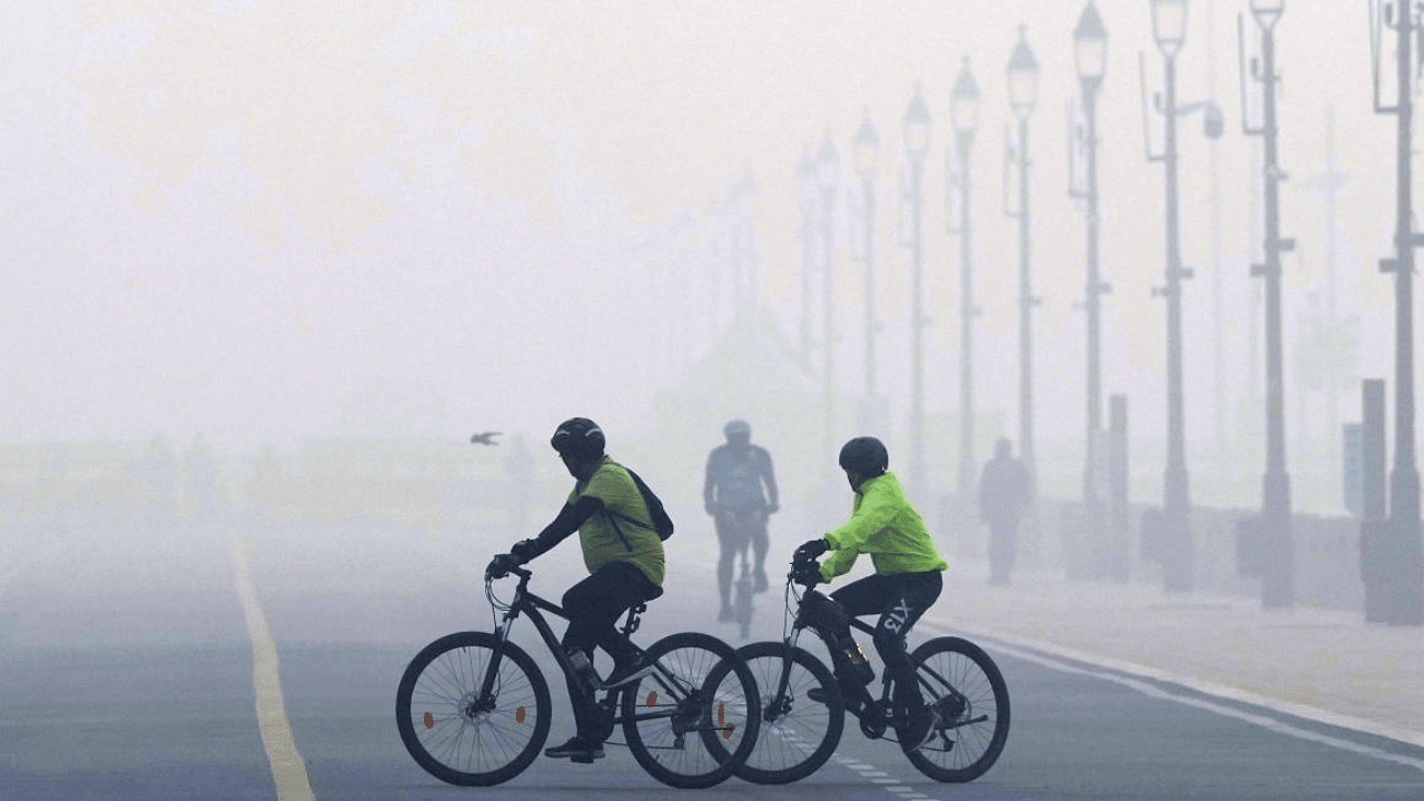 Cyclists ride near India Gate amid low visibility due to smog. Credit: PTI Photo