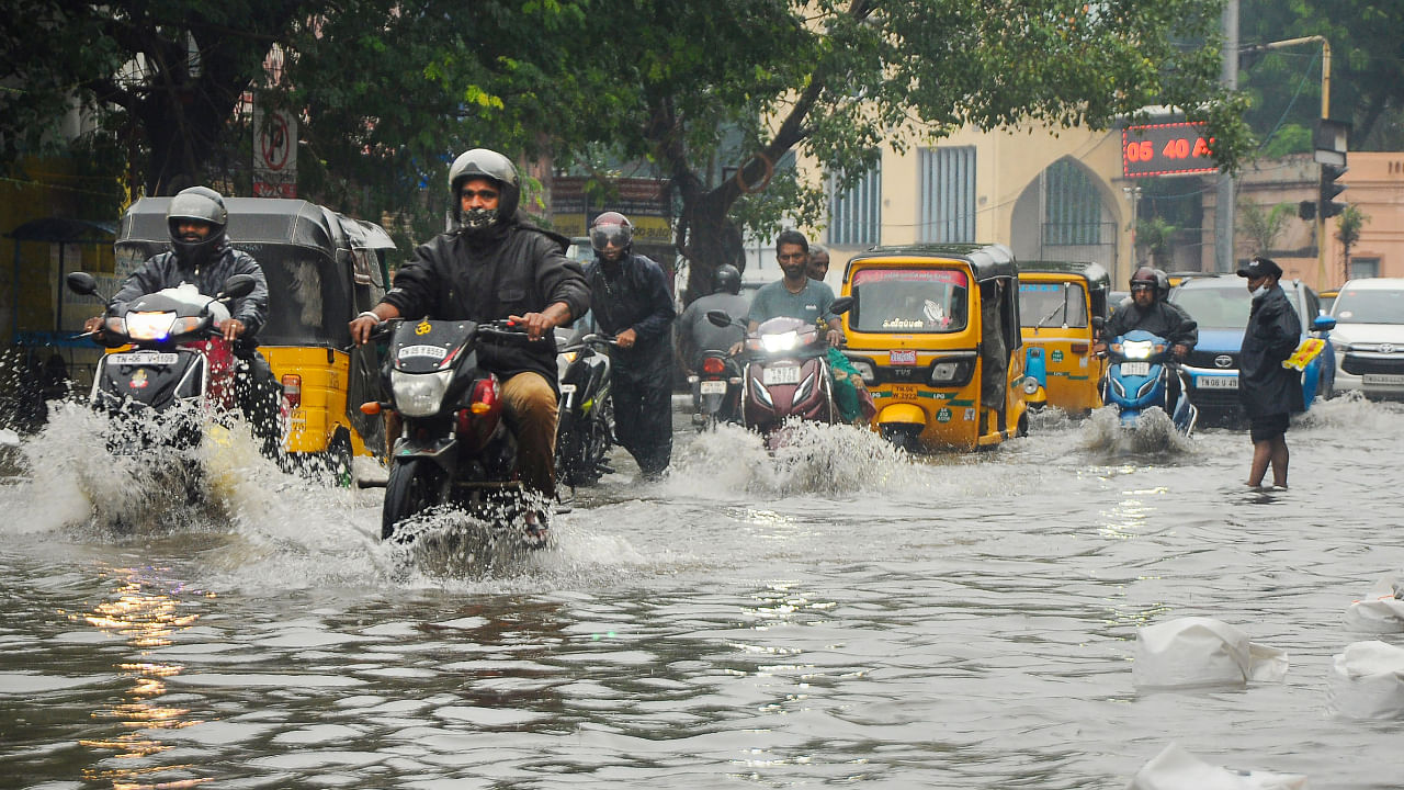 Commuters wade through a waterlogged road following incessant rains, in Chennai. Credit: PTI Photo