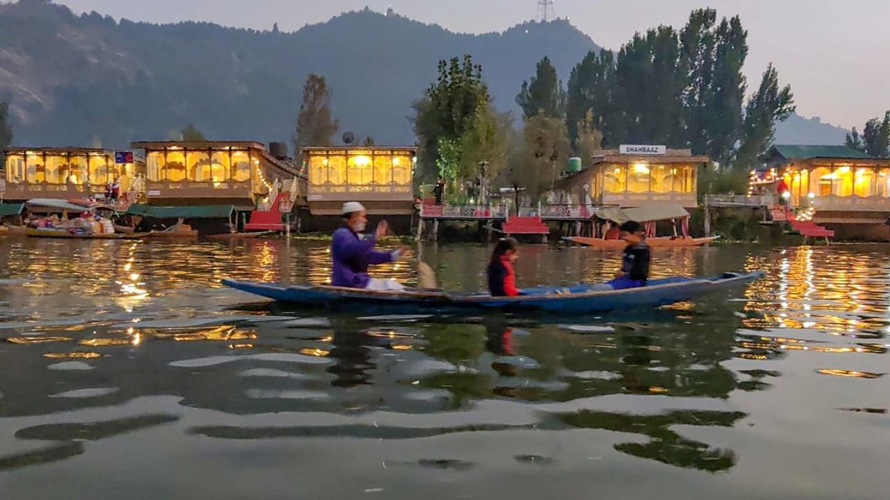 A shikara passes by a row of illuminated houseboats in the picturesque Dal Lake in Srinagar in Jammu & Kashmir. Photo Credit: PTI Photo