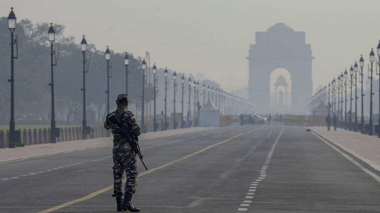 A security person stands guard at Kartavya Path amid low visibility due to smog, in New Delhi. Credit: PTI Photo
