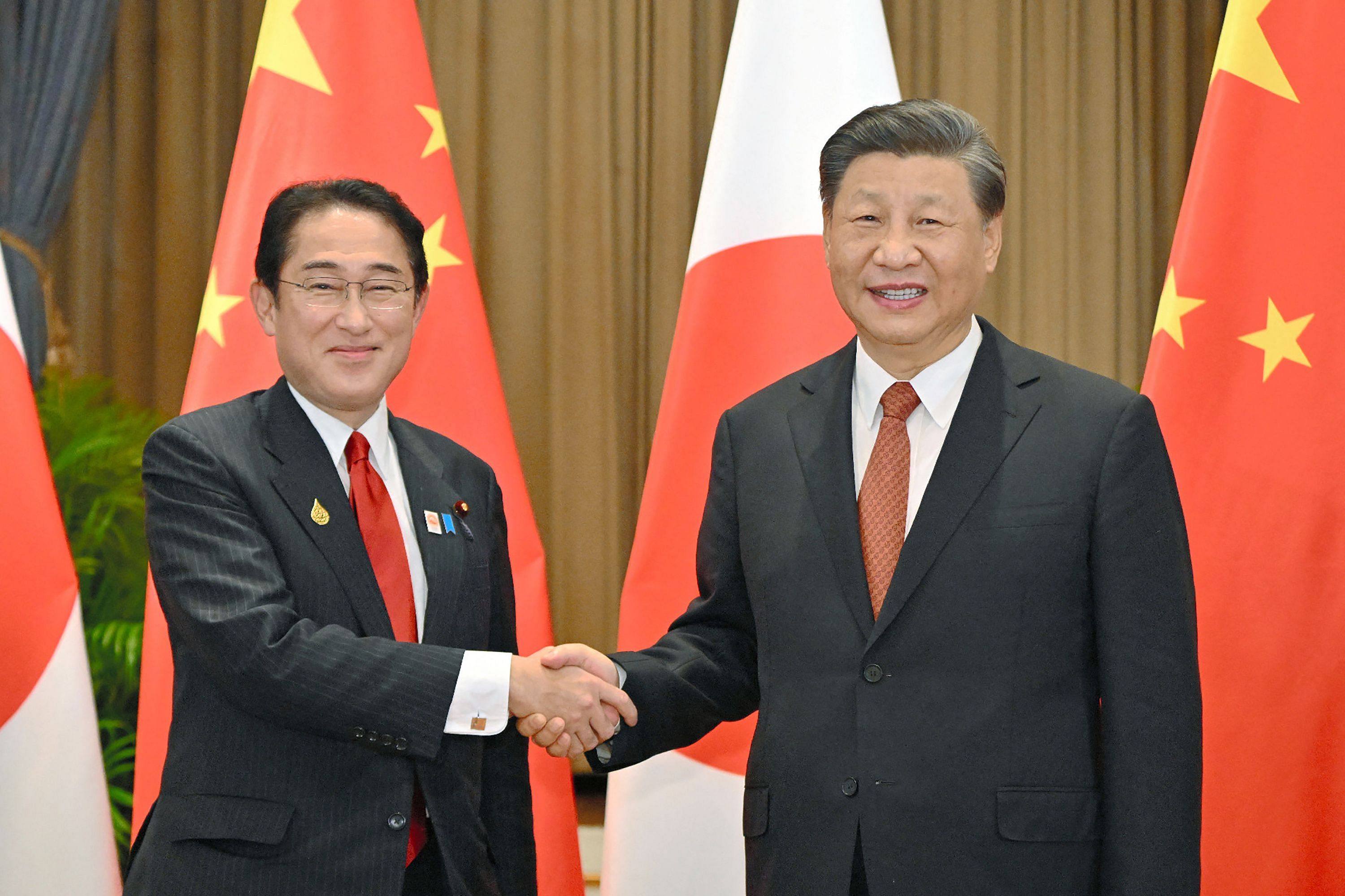 Japan's Prime Minister Fumio Kishida (L) shakes hands with China's President Xi Jinping during their meeting in Bangkok. Credit: AFP Photo