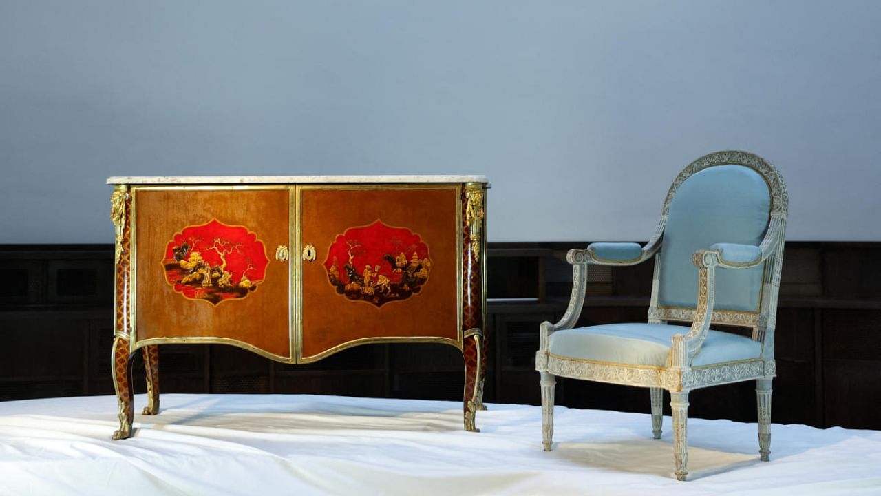 A Royal Late Louis XV Ormolu-Mounted Painted-Tole Commode stamped by Pierre Macret, Cira 1790, and a Royal Louis XVI Cream-Painted Armchair stamped by Georges Jacob, Cira 1788, two pieces of furniture that belonged to the Queen of France, Marie-Antoinette, are displayed before their auction at Christie's auction house in Paris, France, November 16, 2022. Credit: Reuters Photo