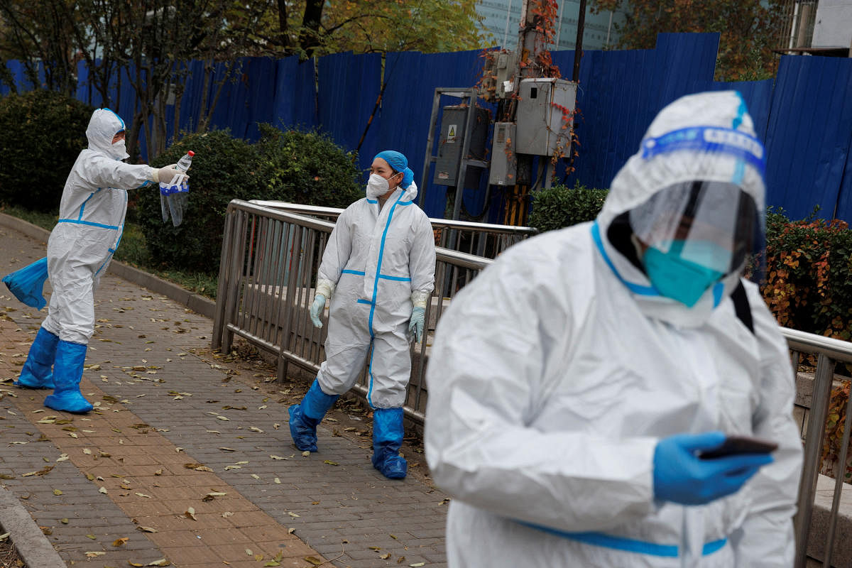 Pandemic prevention workers in protective suits walk outside a locked-down residential compound as outbreaks of the coronavirus disease continue in Beijing. Credit: Reuters Photo