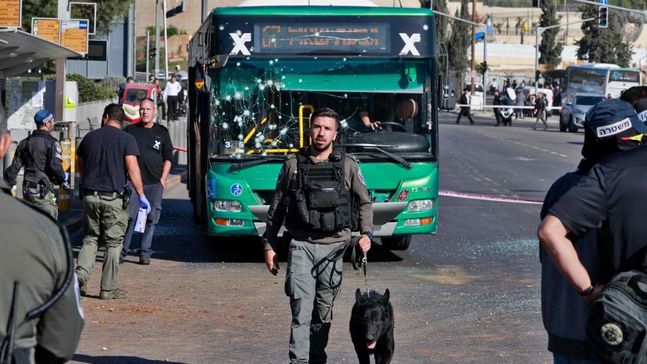 A member of the Israeli security forces holds a sniffer dog at the scene of an explosion at a bus stop in Jerusalem. Photo Credit: AFP