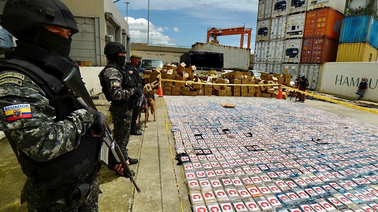 Ecuadorean anti-narcotics police stand guard next to packs of cocaine from a 3-ton shipment seized from a container of bananas, in the port of Guayaquil, Ecuador. Credit: AFP Photo