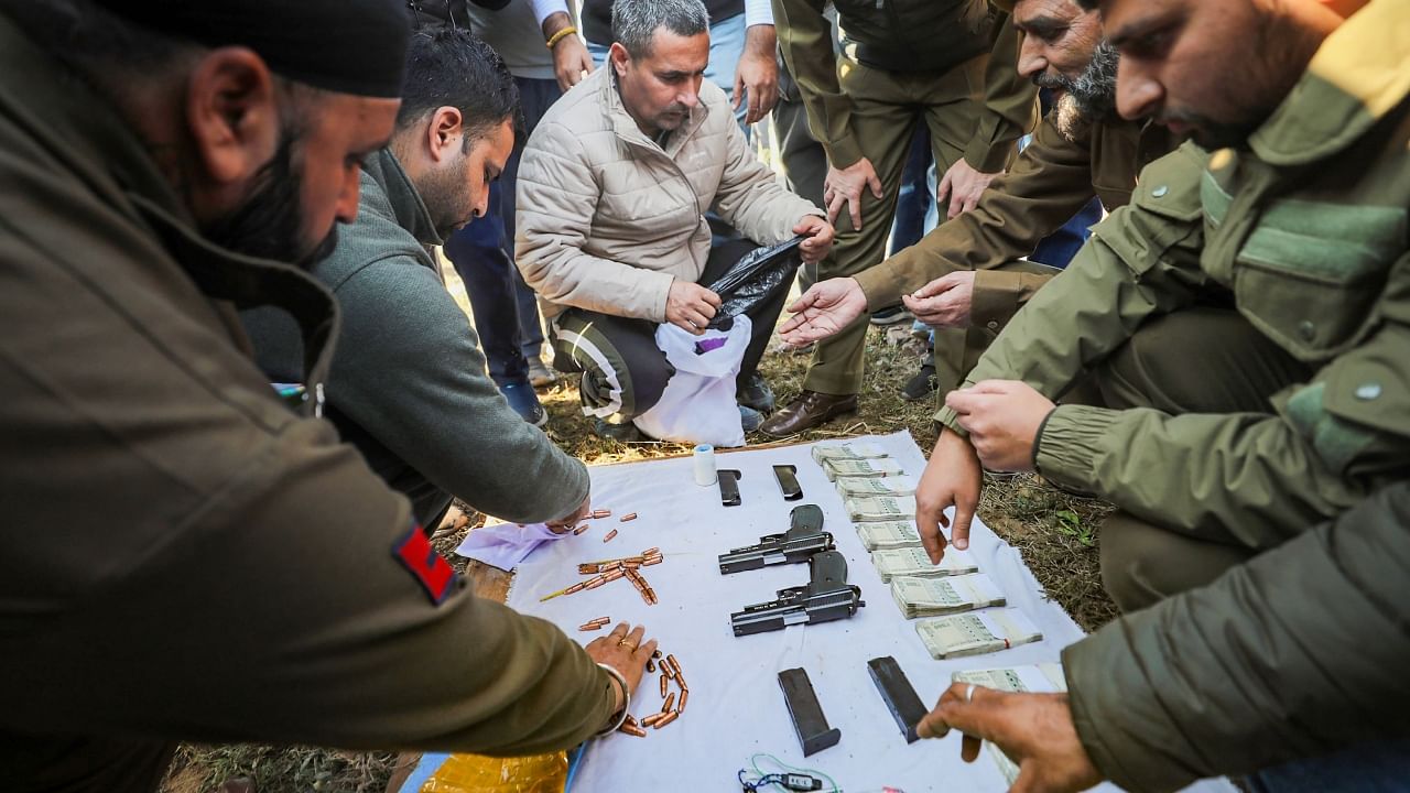 Security personnel display cash, pistols, bullets and other objects recovered from a suspicious packet, believed to be dropped by a suspected Pakistani drone, along the International Border in Samba district of Jammu, Thursday, Nov. 24, 2022. Credit: PTI Photo
