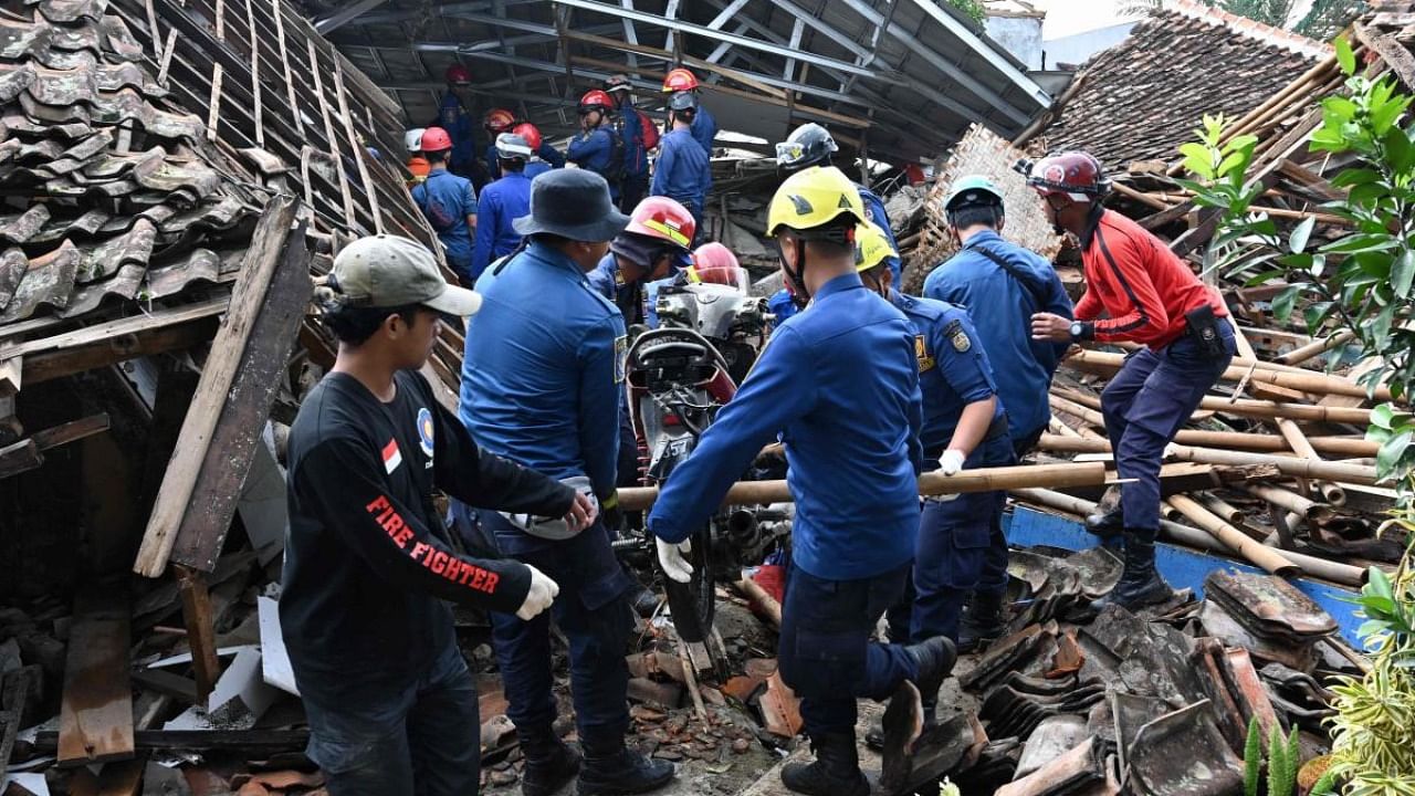 Rescue personnel remove a motorcyle as they work to find a missing child believed to be trapped in the rubble of a collapsed house at Cugenang in Cianjur, West Java. Credit: AFP Photo