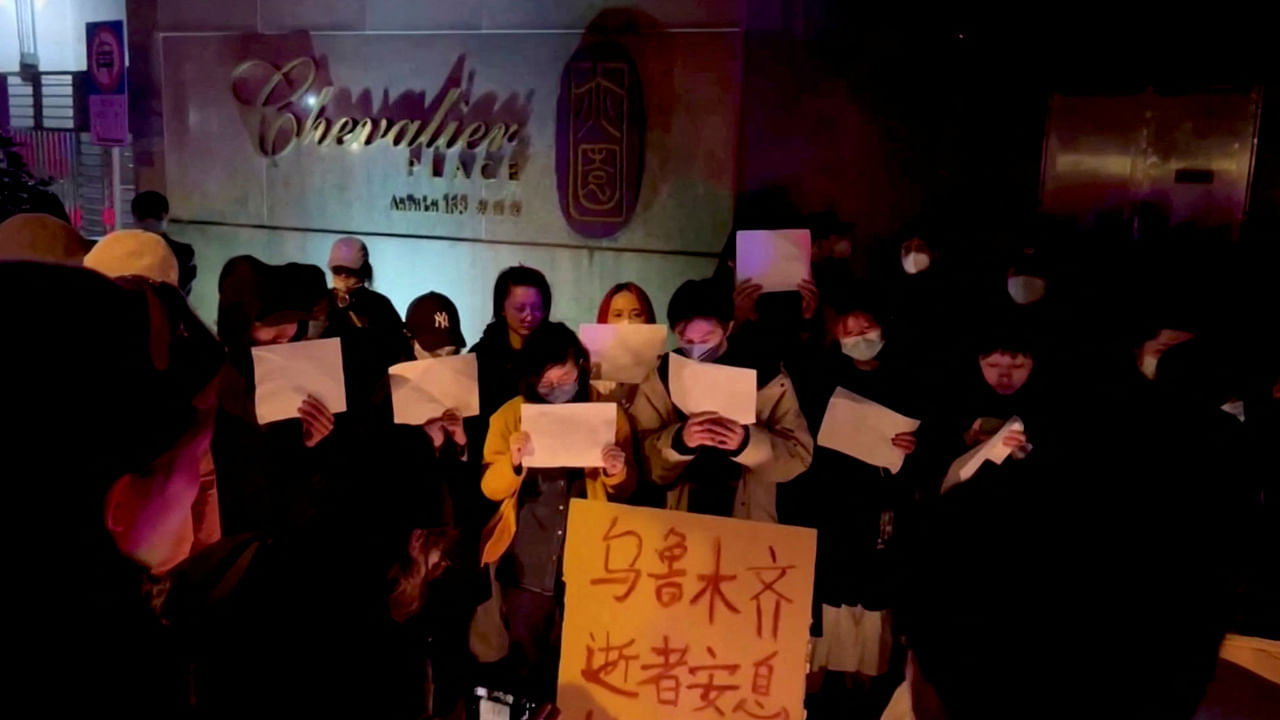People hold signs during a candlelight vigil held for the victims of the Urumqi fire, in Shanghai, China November 26, 2022 in this picture obtained from a social media video. Credit: Gao Ming/via Reuters