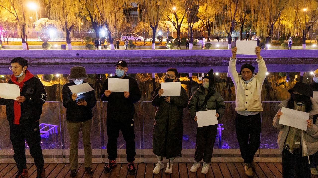 People gather for a vigil and hold white sheets of paper in protest over coronavirus disease (COVID-19) restrictions, during a commemoration of the victims of a fire in Urumqi, as outbreaks of COVID-19 continue, in Beijing. Credit: Reuters Photo