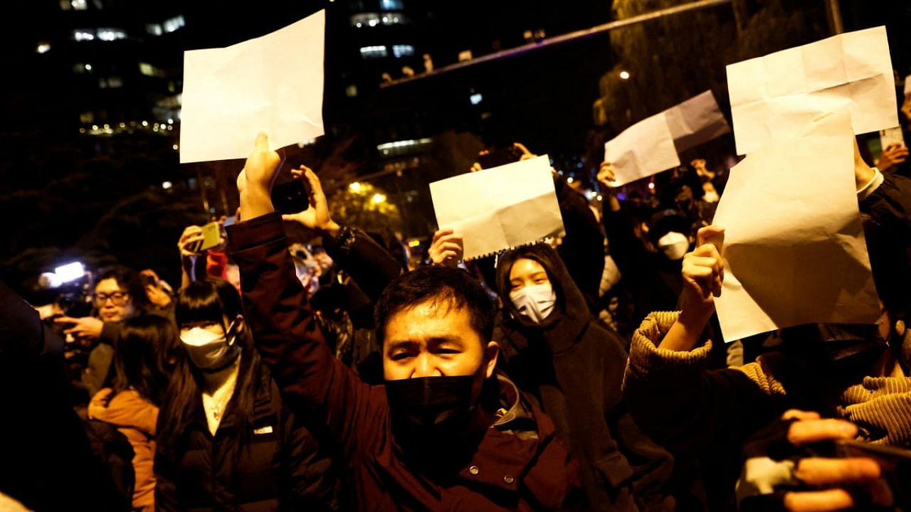 People gather for a vigil and hold white sheets of paper in protest of coronavirus disease (COVID-19) restrictions, as they commemorate the victims of a fire in Urumqi, as outbreaks of the coronavirus disease continue in Beijing, China, November 27, 2022. Credit: Reuters Photo