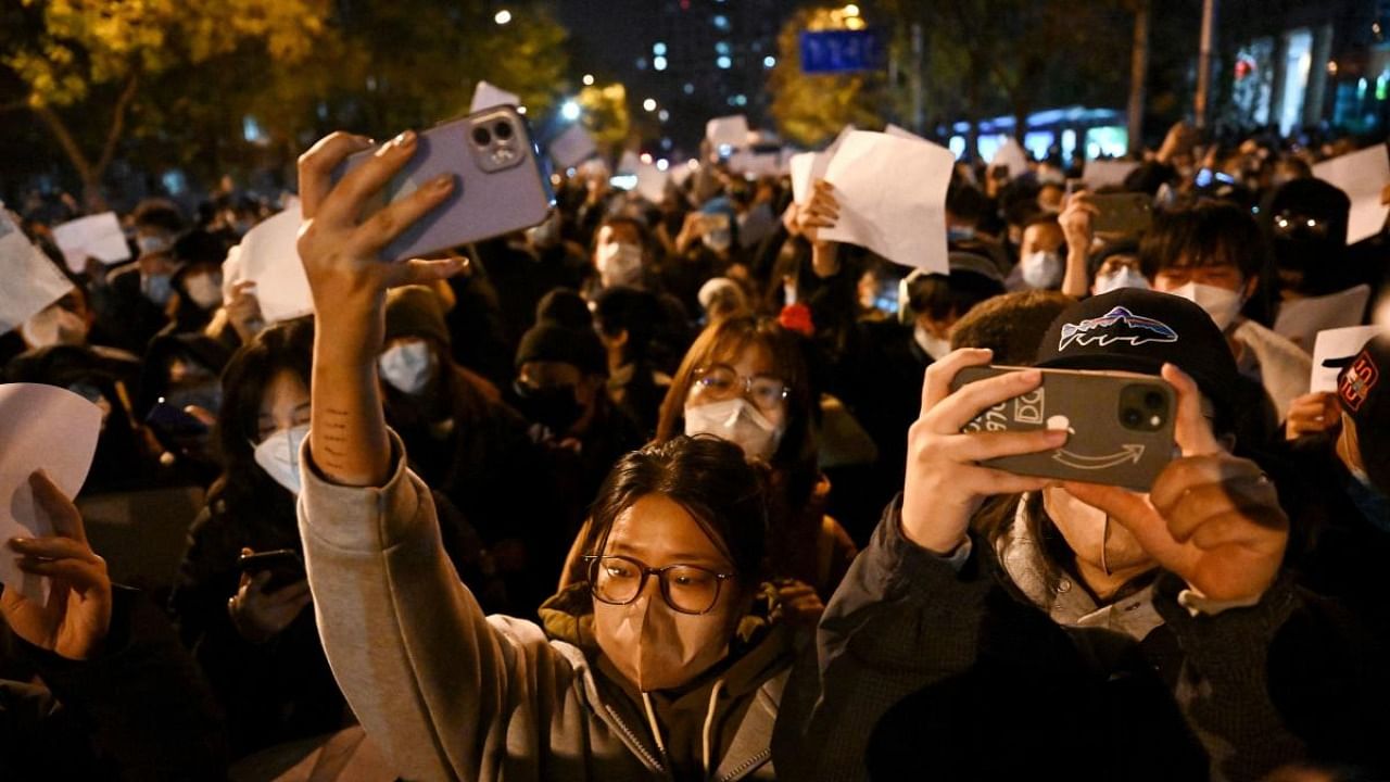 Protesters march along a street during a rally for the victims of a deadly fire as well as a protest against China's harsh Covid-19 restrictions in Beijing on November 28, 2022. Credit: AFP Photo