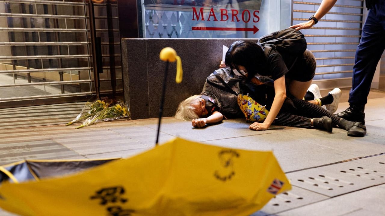 A protester lies on the ground after being pushed during a protest over coronavirus disease restrictions in mainland China. Credit: Reuters photo