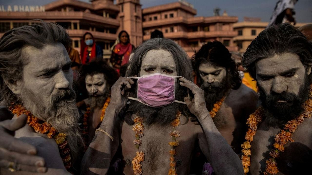 A 'Naga Sadhu,' or Hindu holy man, places a mask across his face before entering the Ganges river during the traditional Shahi Snan, or royal dip, at the Kumbh Mela festival in Haridwar, India, April 12, 2021. Credit: Reuters Photo