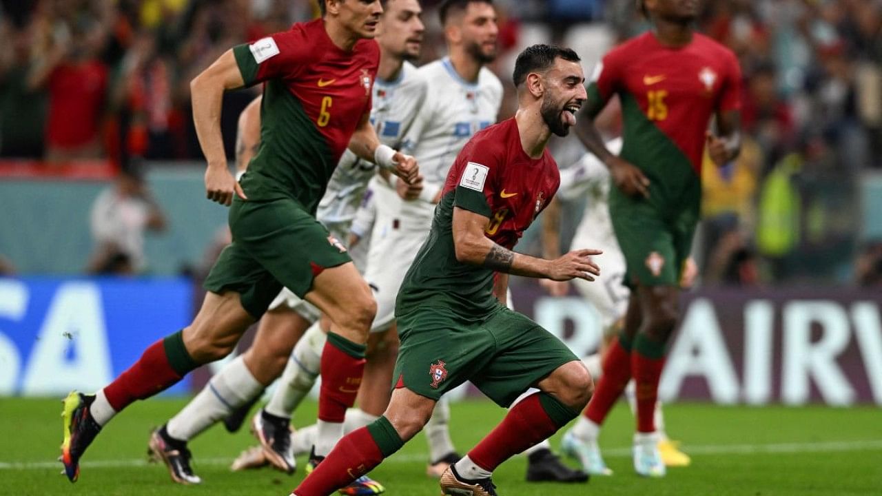 Portugal's midfielder #08 Bruno Fernandes (R) cleebrates after he scored his team's second goal from the penalty shot during the Qatar 2022 World Cup Group H football match between Portugal and Uruguay. Credit: AFP Photo