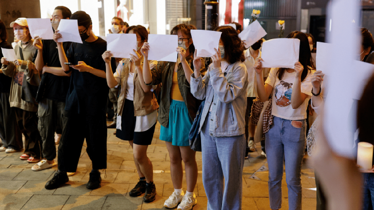 People hold sheets of paper in protest over coronavirus disease restrictions in mainland China. Credit: Reuters Photo