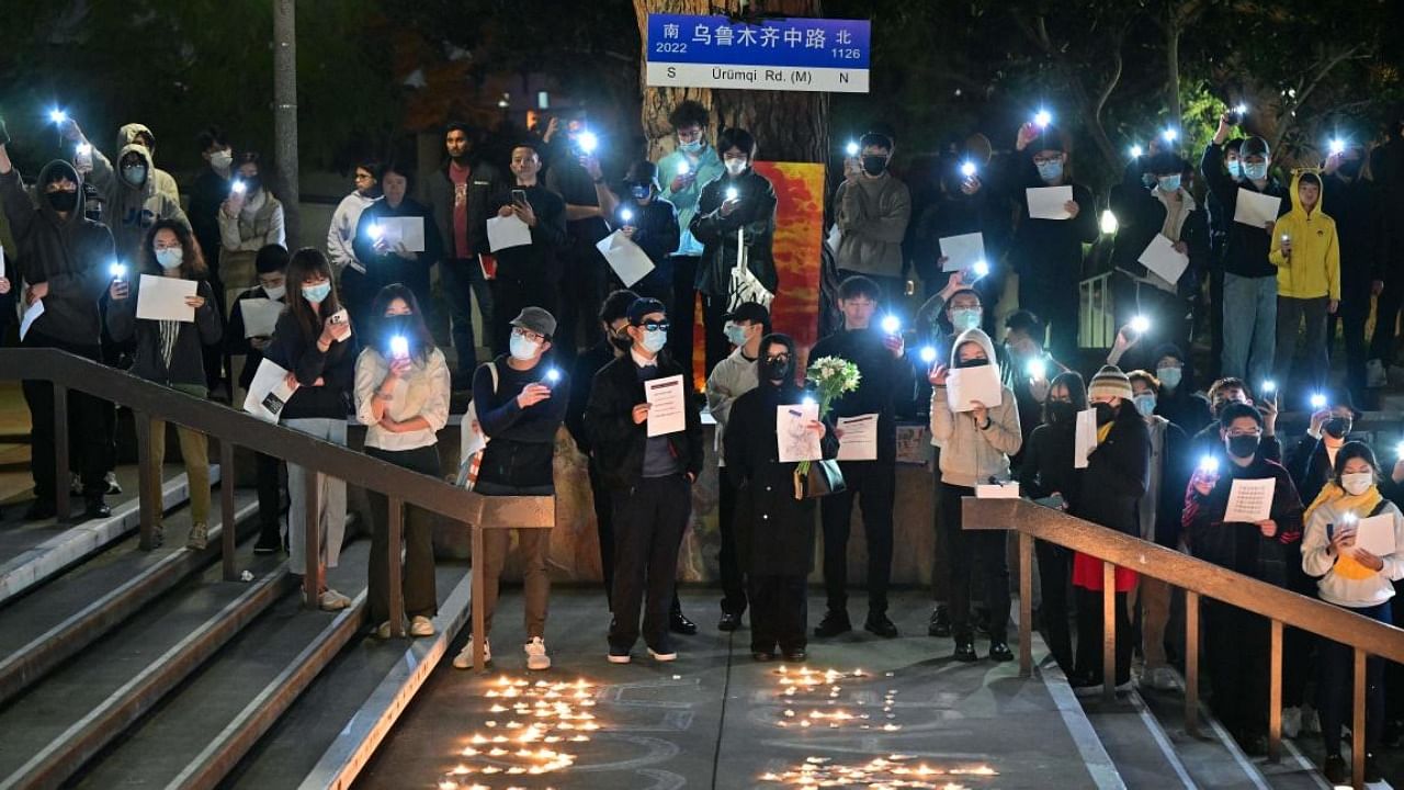 Standing beside a makeshift Urumuqi Road sign, people hold blank sheets of paper while protesting in China. Credit: AFP Photo