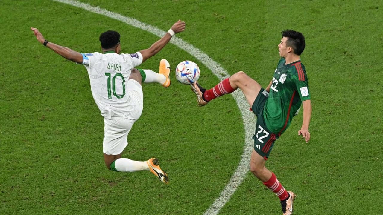 Saudi Arabia's midfielder #10 Salem Al-Dawsari (L) fights for the ball with Mexico's forward #22 Hirving Lozano during the Qatar 2022 World Cup. Credit: AFP Photo