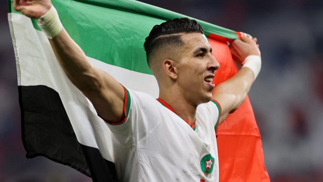 Morocco's Jawad El Yamiq carries the flag of Palestine as he celebrates qualifying for the knockout stages. Credit: Reuters Photo