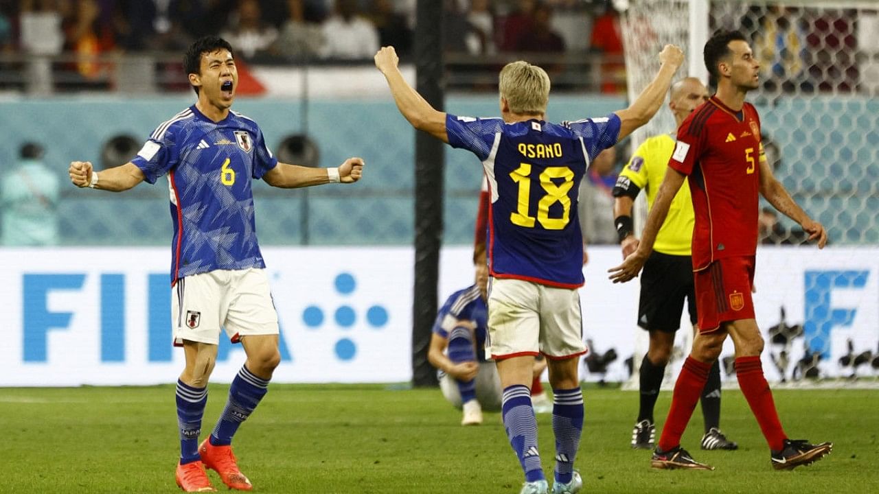 Japan's Wataru Endo and Takuma Asano celebrate after the match as Japan qualify for the knockout stages. Credit: Reuters Photo