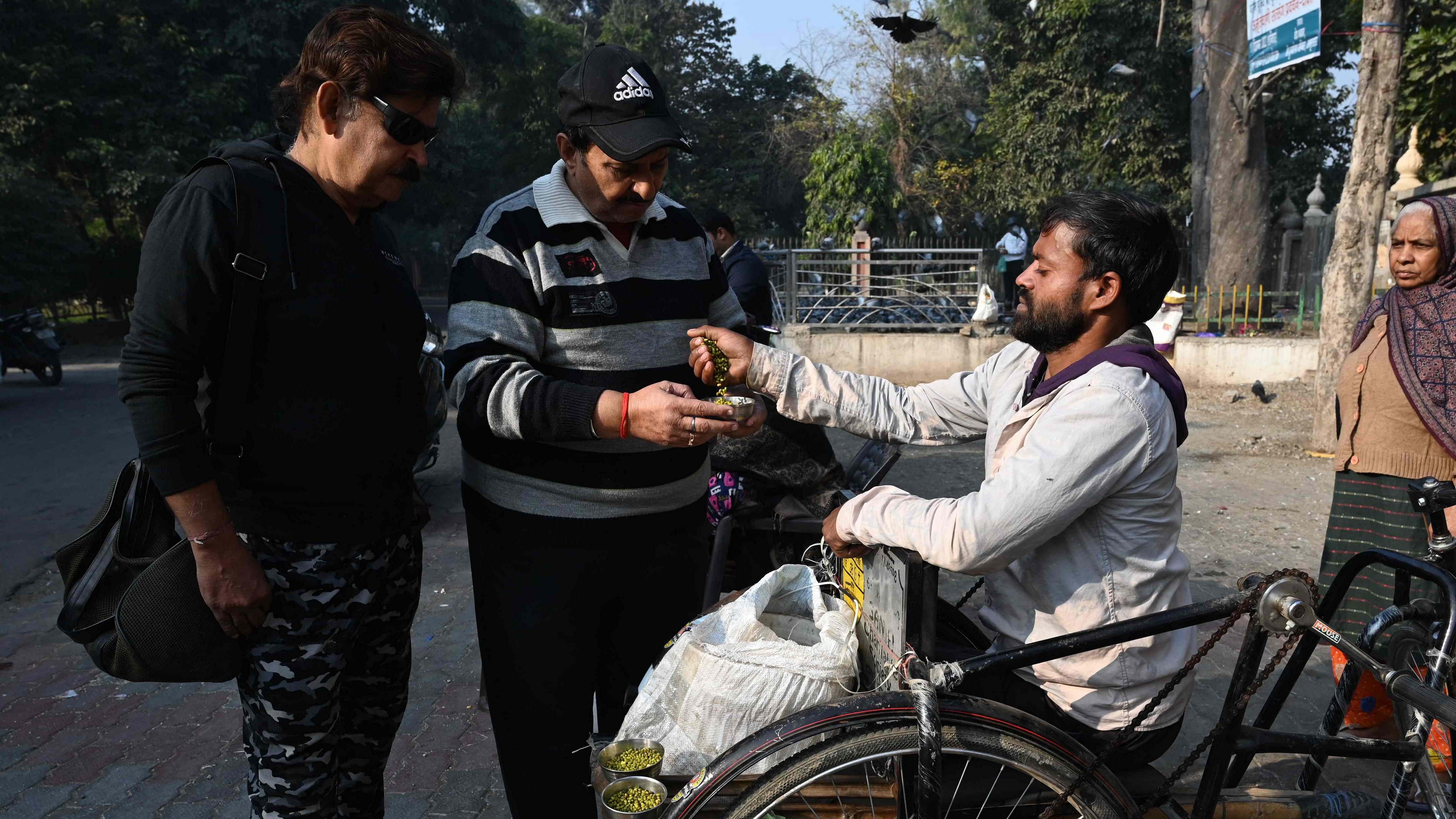 A man with a mobility disabilty sells grains to feed pigeons at a park in Amritsar. Credit: AFP Photo