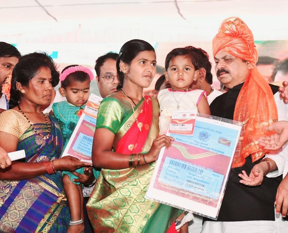 Chief Minister Basavaraj Bommai hands over Bhagyalakshmi bond to a beneficiary at a public programme in Salahalli of Ramadurg taluk in Belagavi district on Friday. Credit: DH Photo