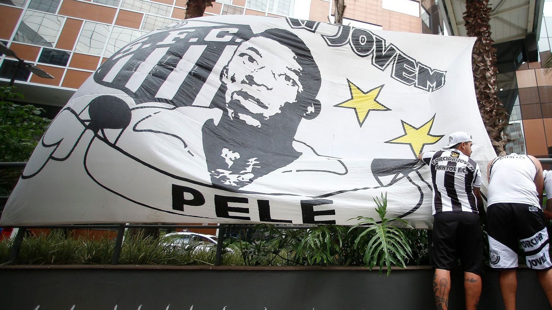  Fans of Santos place a flag with the image of Brazilian football legend Pele during a vigil outside the Albert Einstein Israelite Hospital entrance, where he is hospitalized in Sao Paulo. Credit: AFP Photo