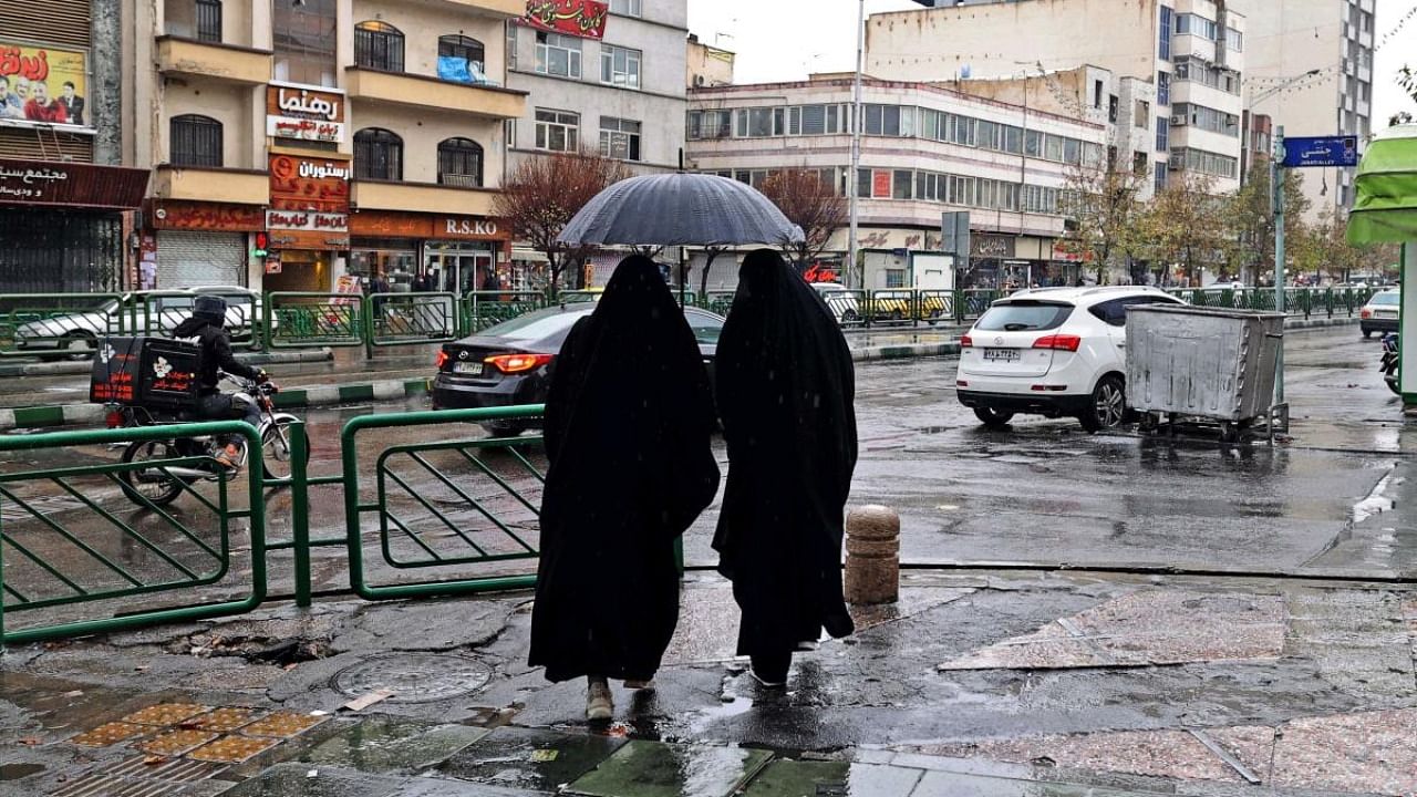 Women share an umbrella as they stand at Enghelab Square in Iran's capital Tehran. Credit: AFP Photo