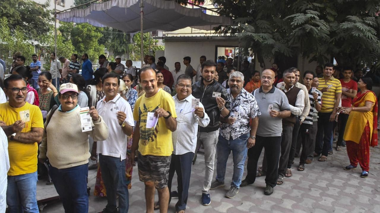 Voters show their identification cards as they wait in a queue to cast their votes at a polling booth during the second and final phase of Gujarat Assembly elections, in Vadodara, Monday, Dec. 5, 2022. Credit: PTI Photo