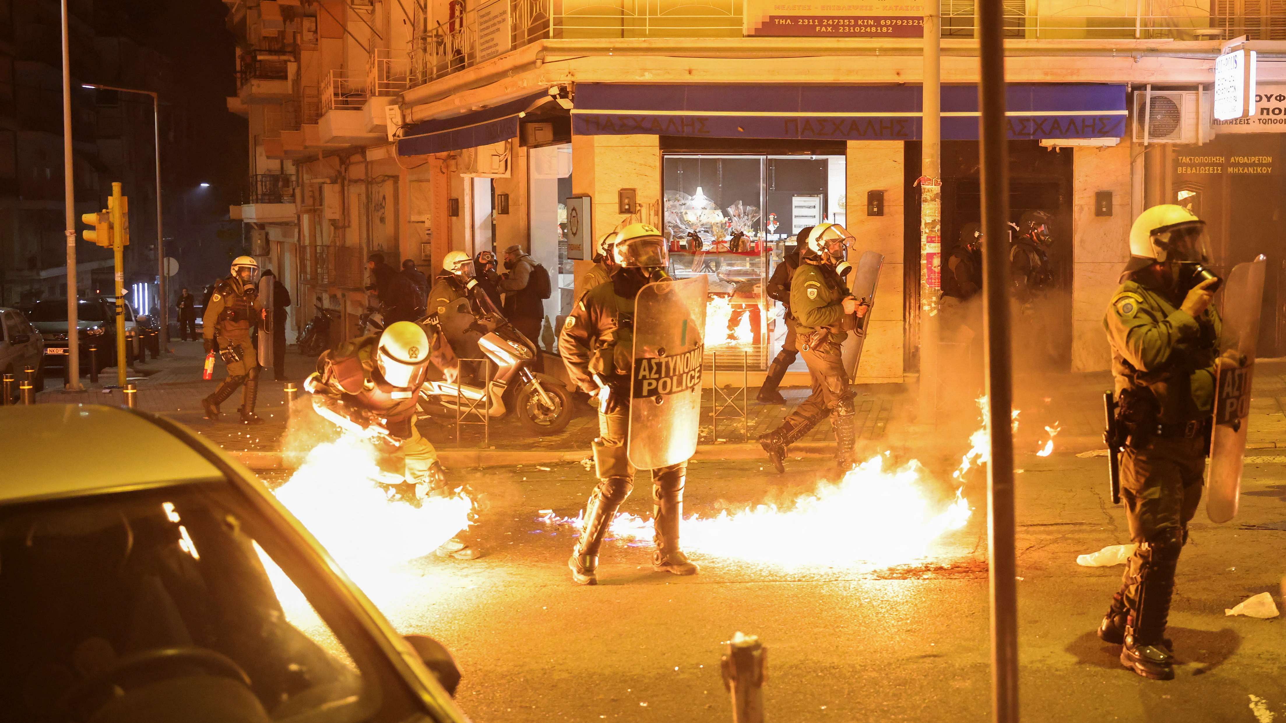 Riot police officers walk next to flames from a petrol bomb during clashes with demonstrators. Credit: Reuters Photo