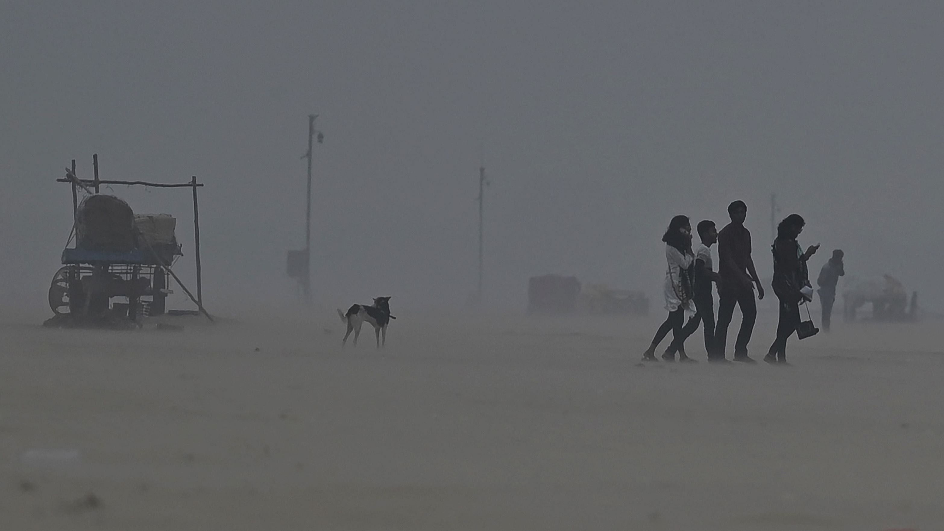 People walk amid heavy winds at Marina beach in Chennai. Credit: AFP Photo