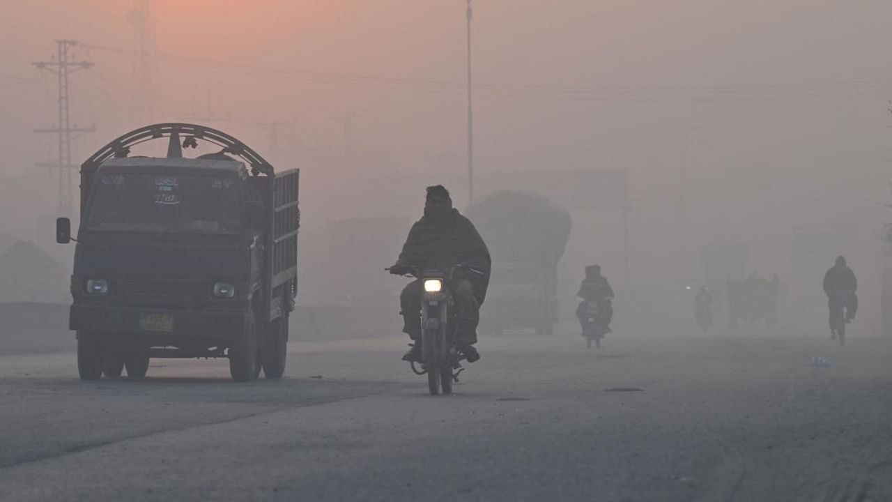 Commuters make their way along a road amid heavy smog conditions in Lahore. Credit: AFP Photo