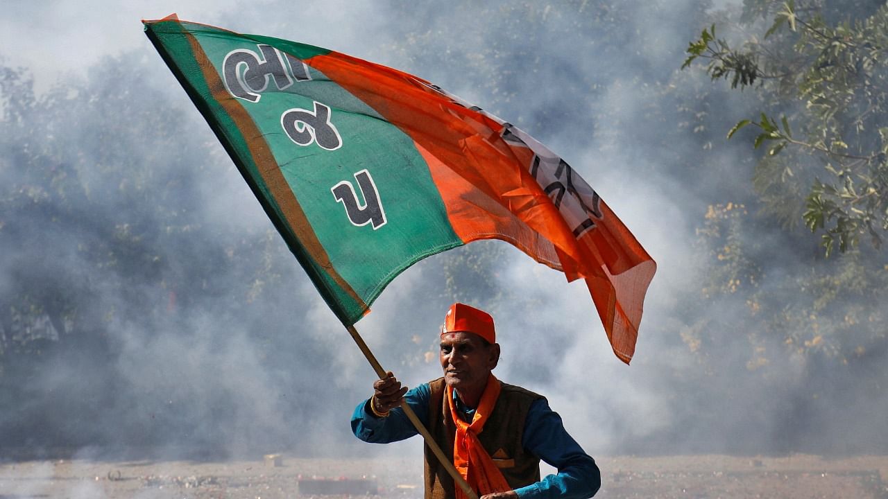 A BJP supporter waves his party's flag during celebrations after learning of the initial poll results of Gujarat Assembly election in Gandhinagar. Credit: Reuters photo
