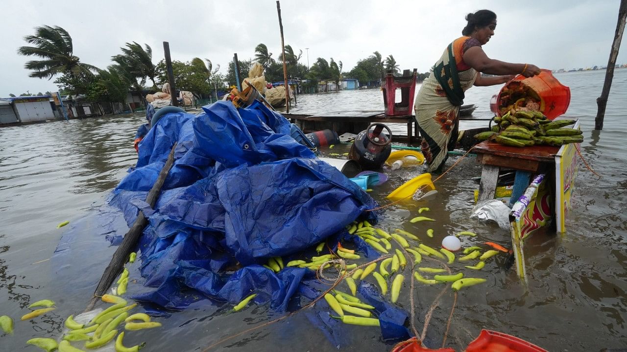 A woman salvages her shop at the Marina beach following the landfall of Cyclone Mandous, in Chennai. Credit: PTI Photo