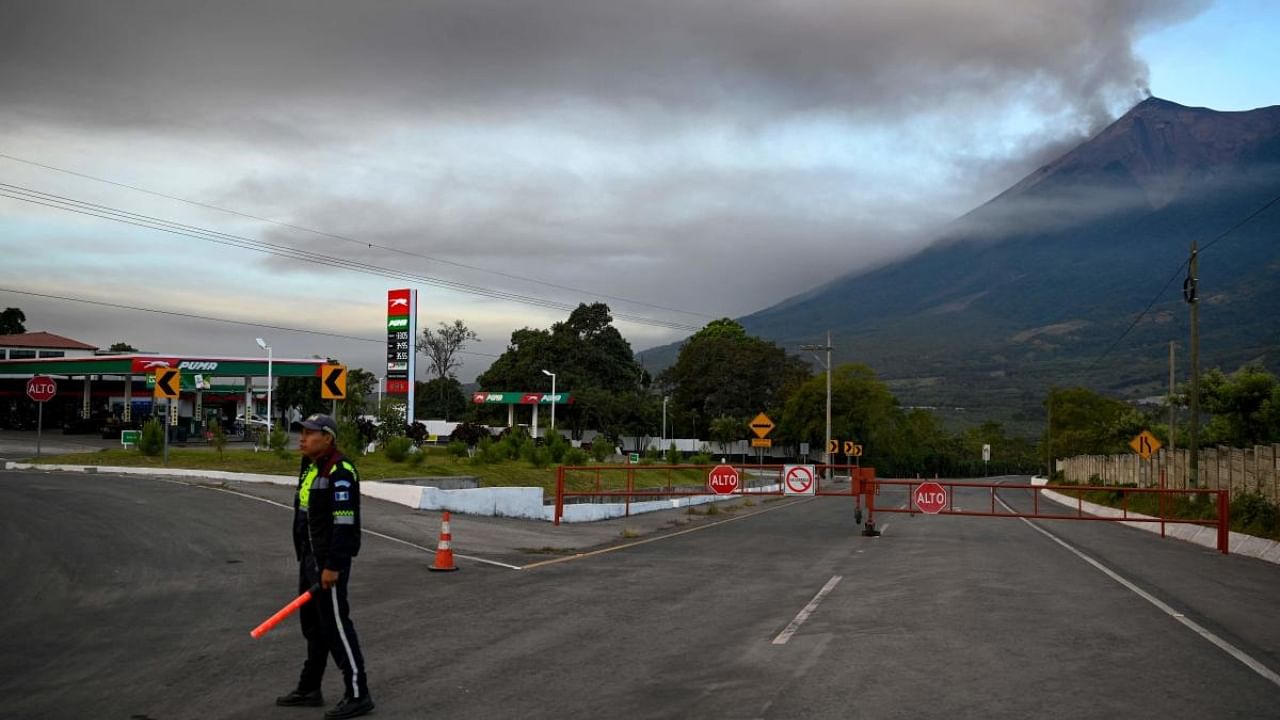 A member of the General Directorate of Road Safety stands next to a closed road after the Fuego volcano erupted. Credit: AFP Photo