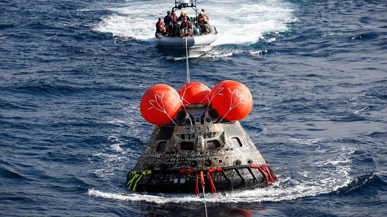US Navy divers attach winch cables to NASA’s Orion capsule after being successfully secured by NASA and US Navy teams off the coast of Baja California, Mexico. Credit: AFP Photo