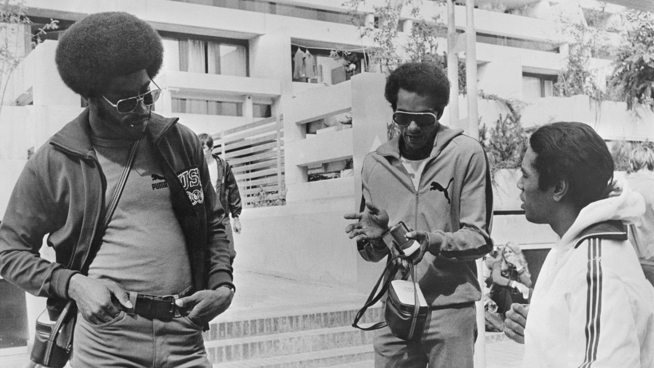 American sprinter John Smith, American sprinter Vince Matthews, and the Swiss team's doctor - and former American athlete - Dave James in conversation during the 1972 Summer Olympics. Credit: Getty Images