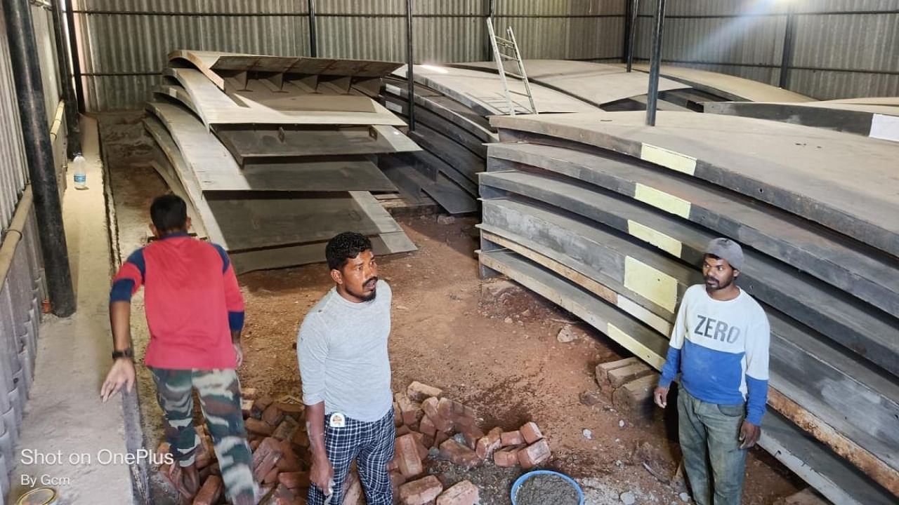 Workers clean the premises where iron gates meant for raising the height of Almatti dam are stored, ahead of the legal team’s visit on December 23. Credit: DH Photo
