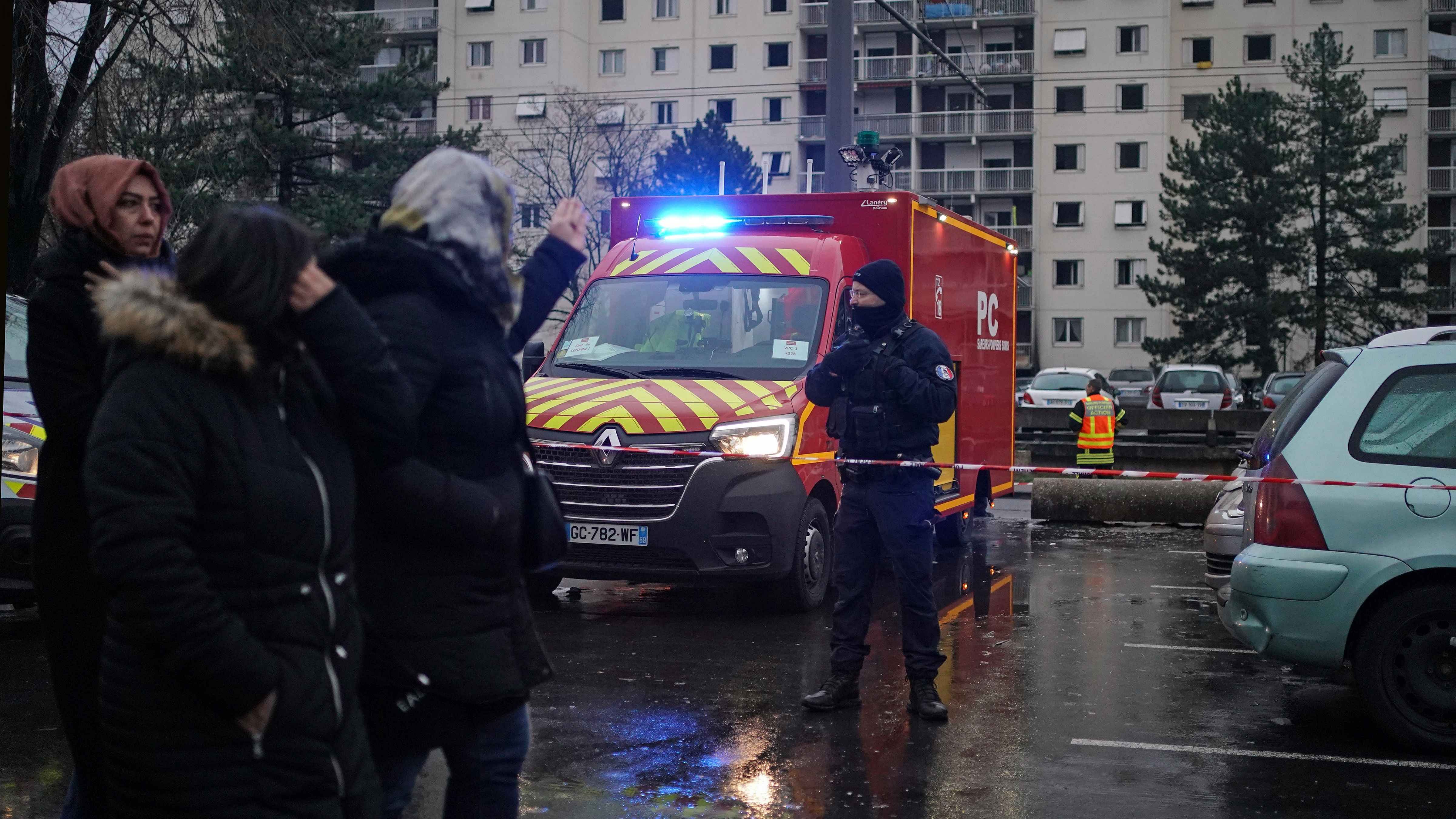 Onlookers walk by a firefighter truck next to apartment buildings seen in background at Le Mas du Taureau neighborhood, in Vauls en Velin, outside Lyon. Credit: AP/PTI Photo