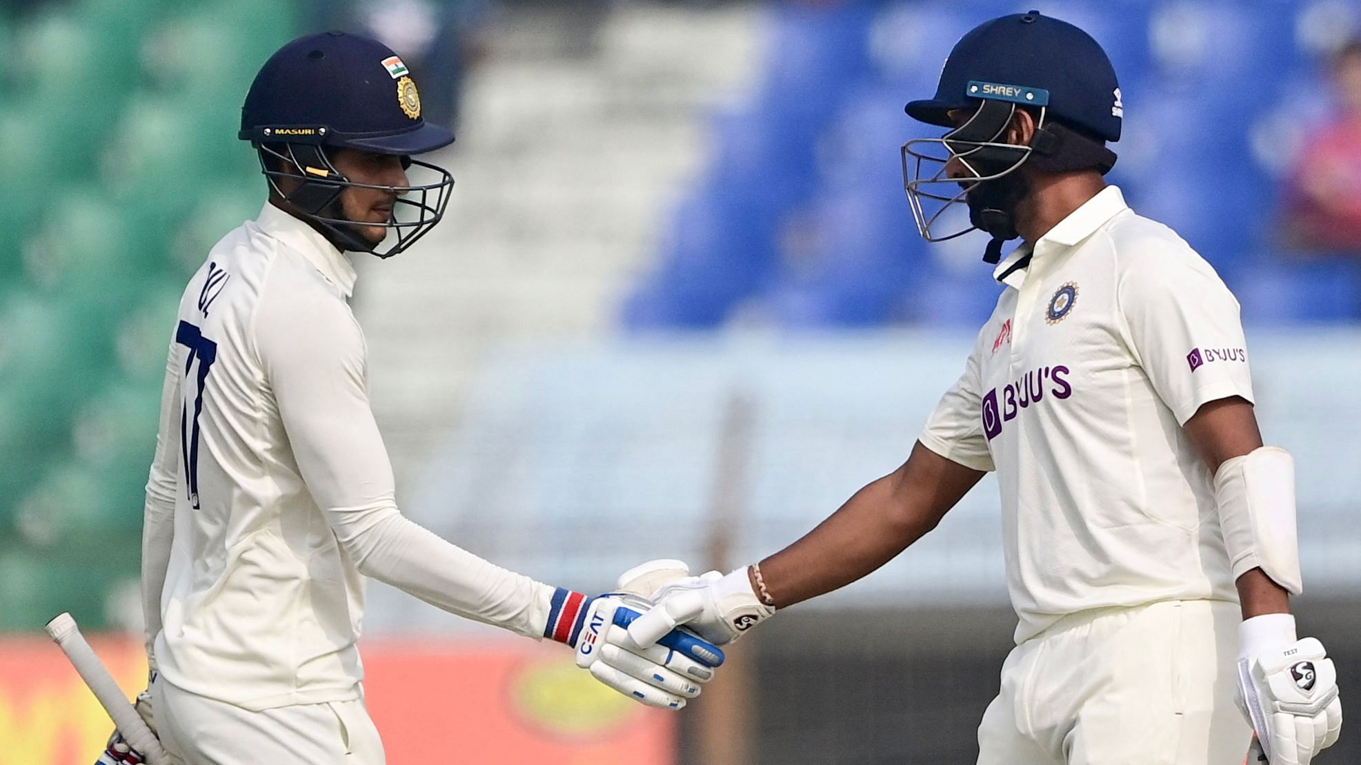 India’s Shubman Gill (L) shakes hand with his teammate Cheteshwar Pujara (R) after scoring a half century. Credit: AFP Photos