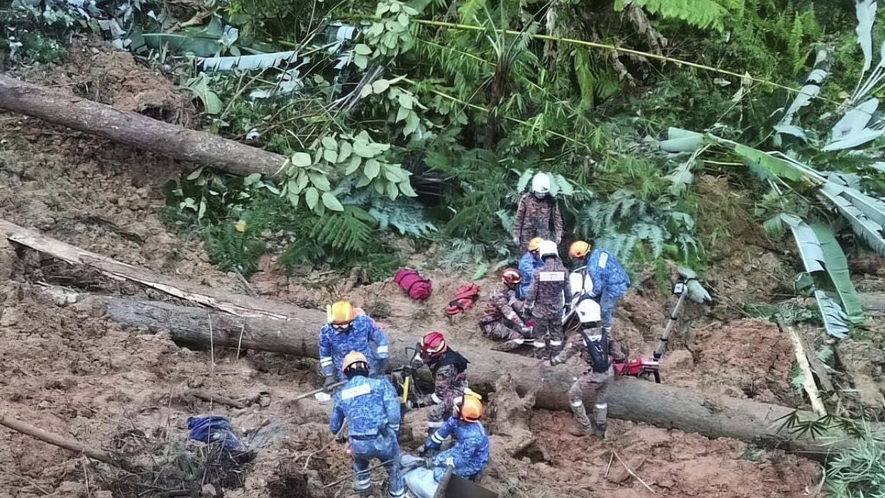Civil Defense personnel search for missing persons after a landslide hit a campsite in Batang Kali, Malaysia