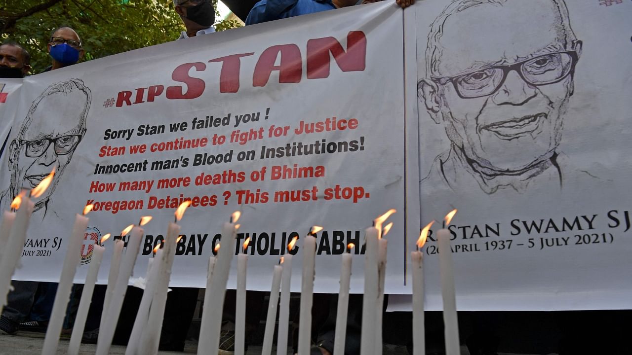 People hold posters next to candles outside the church holding memorial mass for the Indian rights activist and Jesuit priest Father Stan Swamy, in Mumbai on July 6, 2021. Credit: AFP File Photo