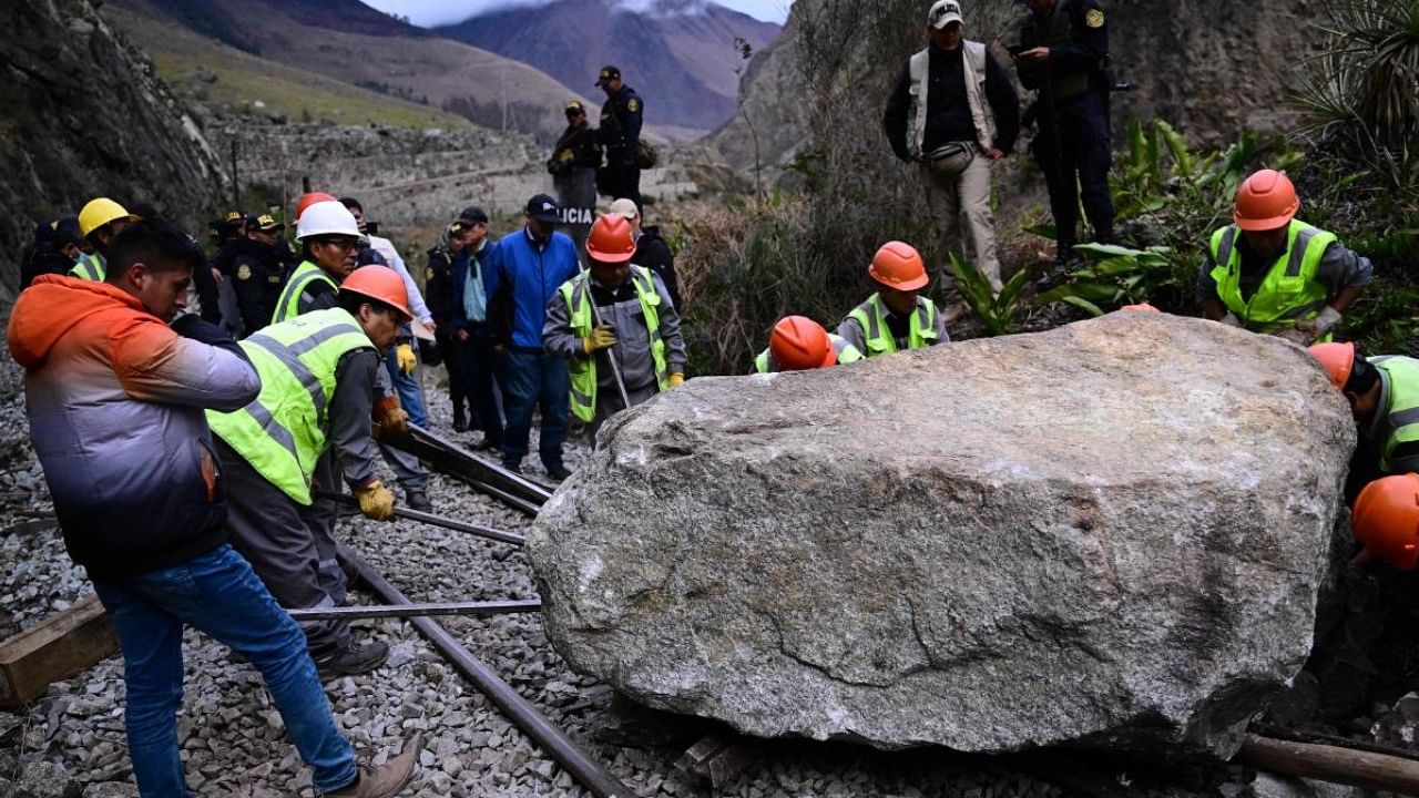 Workers attempt to remove a rock placed by rioters on the railway track to block the train's passage to and from the Inca citadel of Machu Picchu in Peru. Credit: AFP Photo