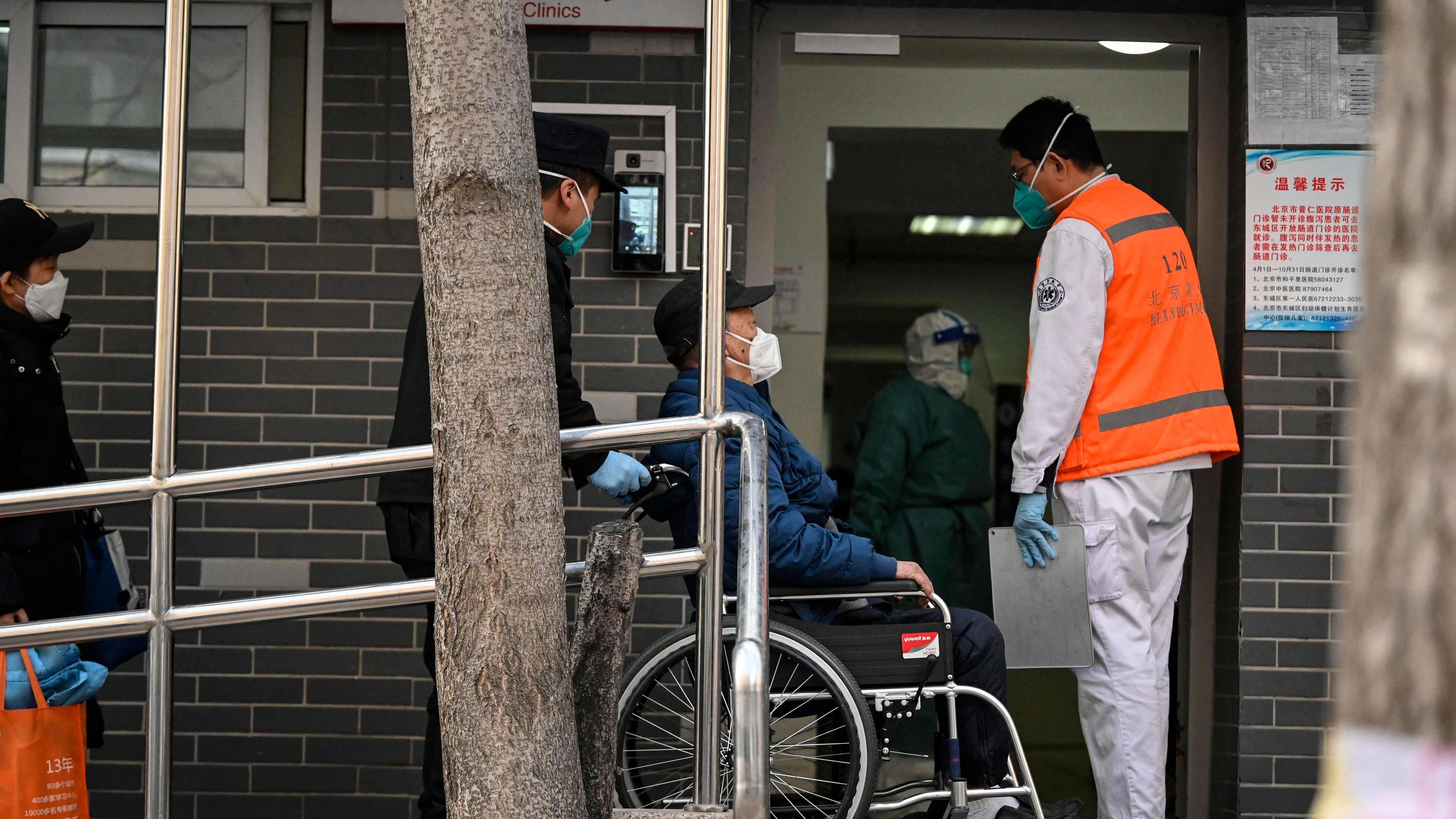 A man on a wheelchair assisted by emergency health workers arrives at a fever clinic amid the Covid-19 pandemic in Beijing on December 20. Credit: AFP Photo