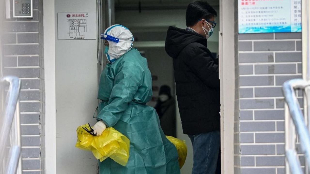 A health worker in personal protective equipment (PPE) carrying medical garbage is seen at a fever clinic amid the Covid-19 pandemic in Beijing on December 20, 2022. Credit: AFP Photo