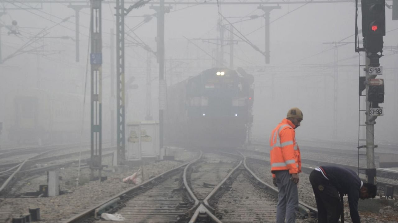A train passes through a railway station amid low visibility due to dense fog on a cold winter morning, in Amritsar. Credit: PTI 